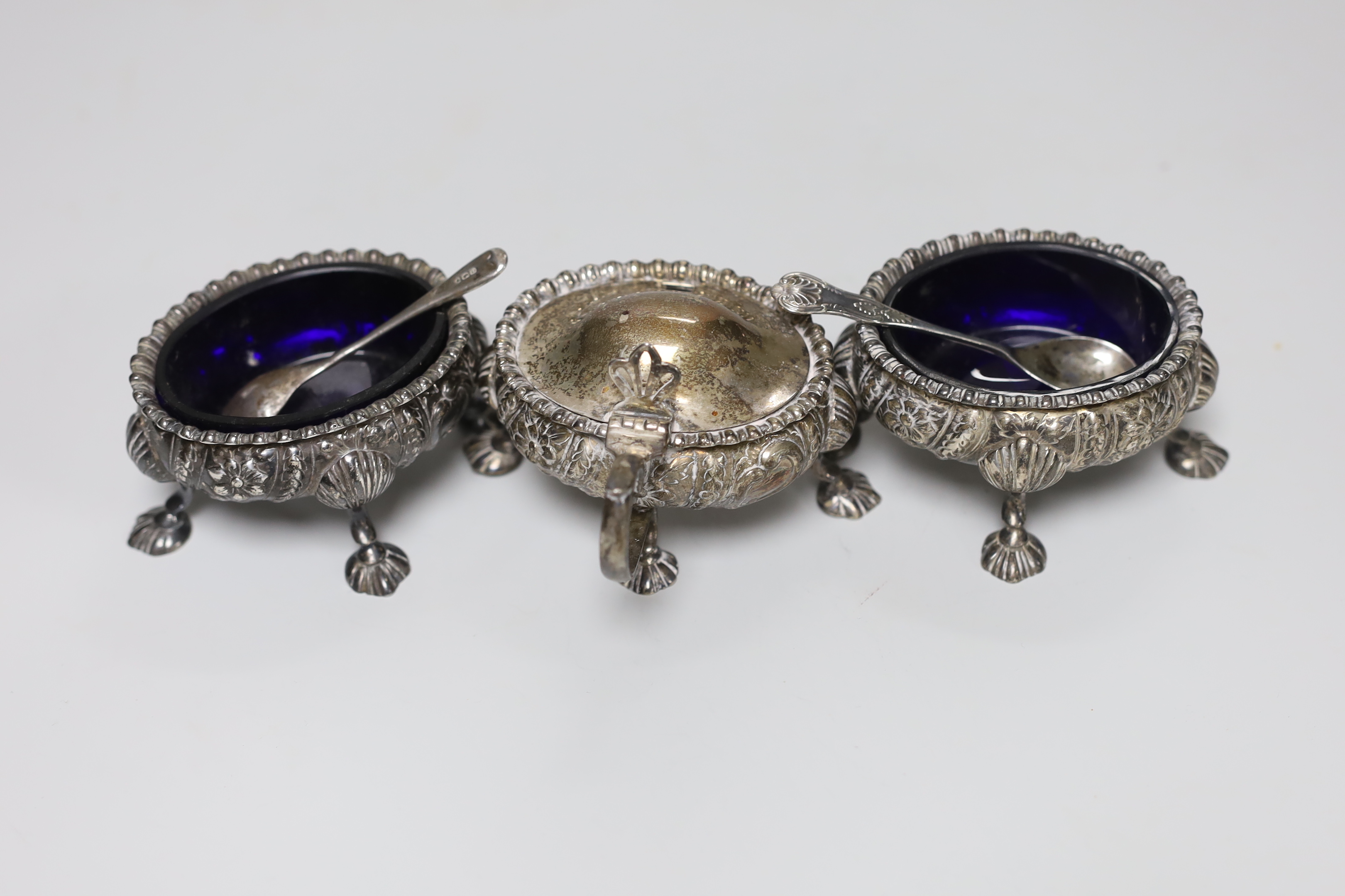 A George V five piece silver condiment set, William Hutton & Sons, Sheffield, 1928, with two associated spoons, one plated.